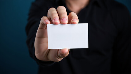 A person in a black shirt holding a blank white business card in their hand close to the camera