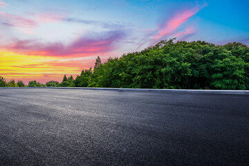 Empty asphalt road and green forest with beautiful sky clouds at sunset