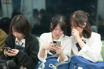 On a spring morning in the Shanghai subway, a group of Japanese high school girls in school uniforms sit on train seats, each quietly lost in her own thoughts during a calm commute in a foreign city.