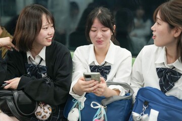 On a spring morning in the Shanghai subway, a group of Japanese high school girls in school uniforms sit on train seats, each quietly lost in her own thoughts during a calm commute in a foreign city.