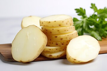 Freshly cut raw potatoes with sliced pieces and green parsley on a wooden board