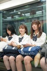 On a spring morning in the Shanghai subway, a group of Japanese high school girls in school uniforms sit on train seats, each quietly lost in her own thoughts during a calm commute in a foreign city.