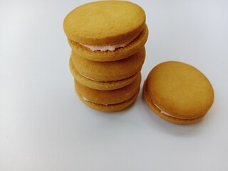 Stack of sandwich cookies with pink cream filling isolated on white background. Sweet vanilla biscuits with creamy center. Perfect for snack or dessert concepts.