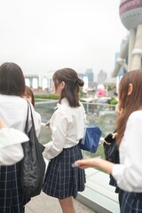 In early summer in Shanghai, near The Bund, Japanese high school girls in uniforms chat and laugh...