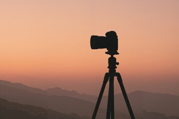 Tripod and camera silhouetted against colorful sunrise backdrop  