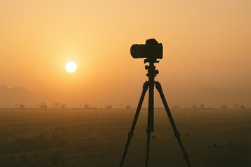 Tripod and camera silhouetted against the sunrise in the morning  