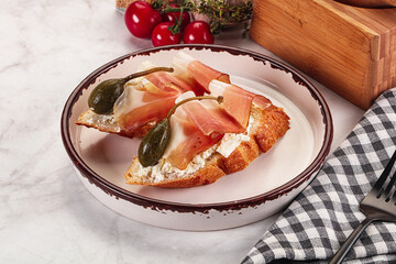 Bruschetta with jamon and caper berries