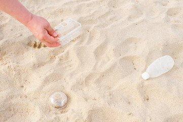 Man pick up plastic garbage on beach on the sand top view.