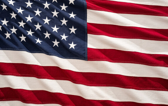 Bright colors of the American flag ripple gracefully in the breeze, showcasing its stars and stripes during a sunny day, representing national pride.