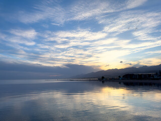 Quiet mountain lake, evening light on the water, Kyrgyzstan. Still water and mountain reflection in the lake.