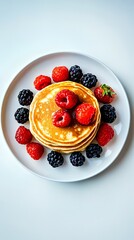 Delicious stack of pancakes topped with fresh berries on a white plate.