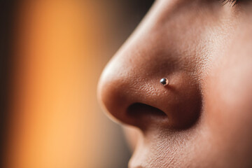 Close-up of delicate silver nose stud on female skin in warm light