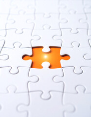 Obraz premium A white jigsaw puzzle with one missing piece reveals a glowing orange background underneath, symbolizing a missing element or solution