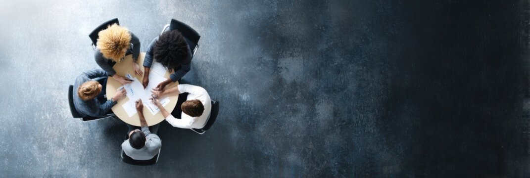 Team Meeting Huddle Observed From Above With a Clean Workspace and Engaged Participants Discussing Ideas and Strategies