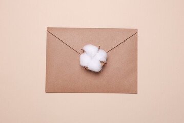 Kraft envelope and cotton flower on beige background.