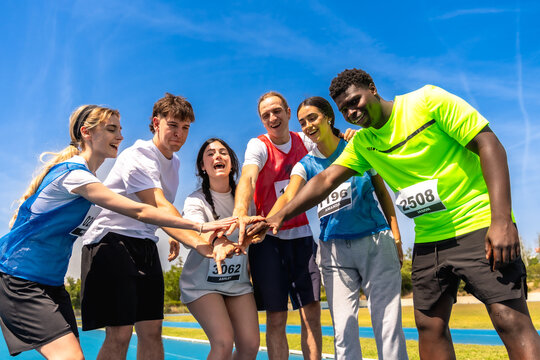 Young athletes joining hands before track and field competition - Powered by Adobe