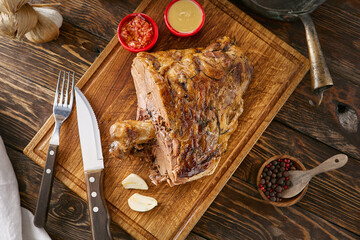 Bone-in roasted meat on wooden board, rustic lighting, overhead composition