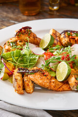 Grilled fish assortment with lime and salad, rustic lighting, overhead composition