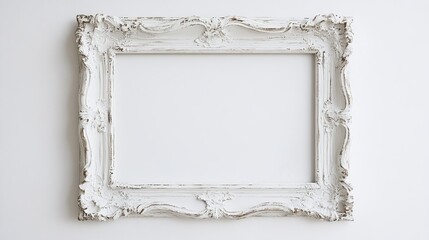 A white, ornate picture frame with a distressed finish sits against a white backdrop, its intricate carvings creating a sense of classic elegance