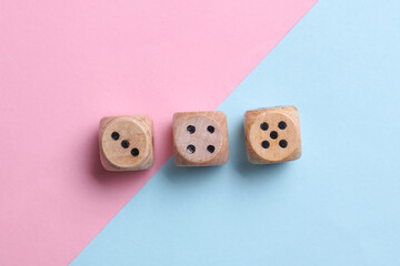 Wooden dice on blue pink pastel background