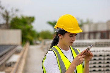 Female civil engineer is using tablet or smart phone conducting a quality check in a precast...
