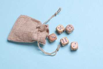 Mini burlap bag with wooden dice on blue background