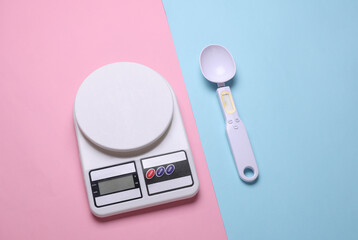 Electronic kitchen scales and smart spoon on pink blue background