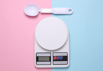 Electronic kitchen scales and smart spoon on pink blue background