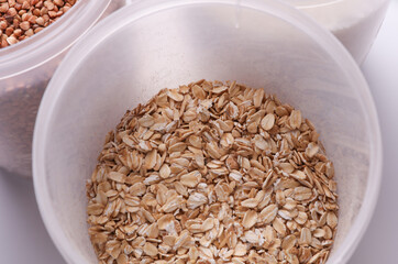 Plastic jars with buckwheat, oatmea on white background. Top view