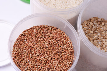 Plastic jars with buckwheat, oatmea and rice on white background. Top view