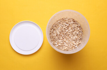 Plastic jars with oatmea on yellow background. Top view
