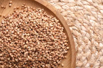 Buckwheat groats in a wooden bowl on a straw mat