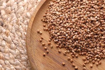 Buckwheat groats in a wooden bowl on a straw mat