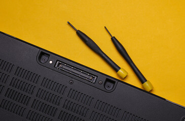 Laptop with screwdrivers on yellow background. Repair of digital equipment and gadgets.