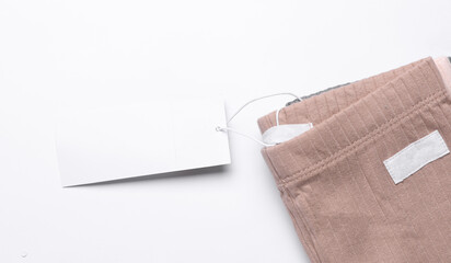 Mockup of white price tag with clothes on white background