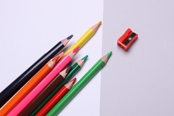 White blank paper sheet and Set of wooden colored pencils with sharpener on gray background