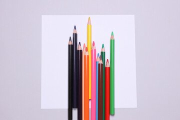 White blank paper sheet and Set of wooden colored pencils on gray background