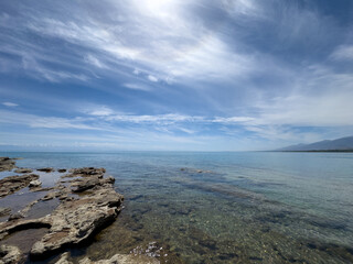 Rocky shore and clear water of Issyk-Kul under a vast sky