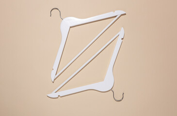 Fototapeta premium White wooden hangers on beige background. Top view. Flat lay