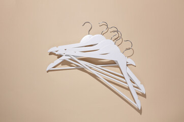 White wooden hanger on beige background. Top view. Flat lay