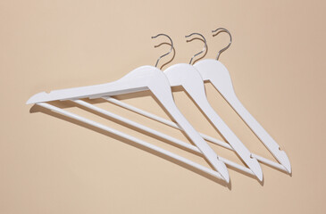 White wooden hangers on beige background. Top view. Flat lay