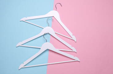 White wooden hangers on pink blue background. Top view. Flat lay