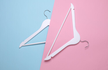 White wooden hangers on pink blue background. Top view. Flat lay