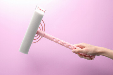 Hand holding window cleaning mop on purple background
