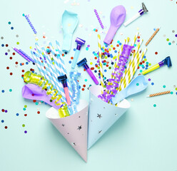 Birthday cone hats with party accessories on blue background. Top view