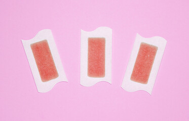 Wax strips for depilation on pink background. Top view