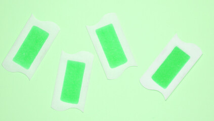 Wax strips for depilation on green background. Top view