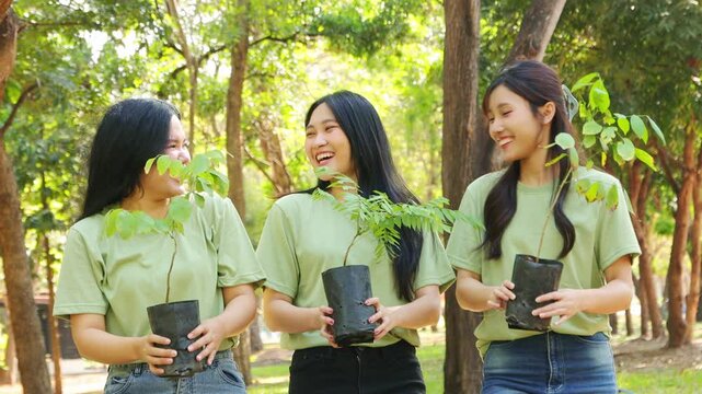 Portrait female volunteer : Group happy female students wearing green shirts show their teamwork as a talented female volunteer campaigner planting trees in a green park sustainable environment. 