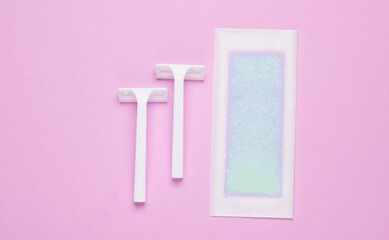 Wax strip for depilation and razors on a purple background. Top view
