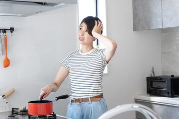 キッチンで料理をしながら悩んでいる女性